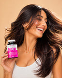 Woman with long dark hair holding a supplement bottle labeled 'GLOW' against a beige background